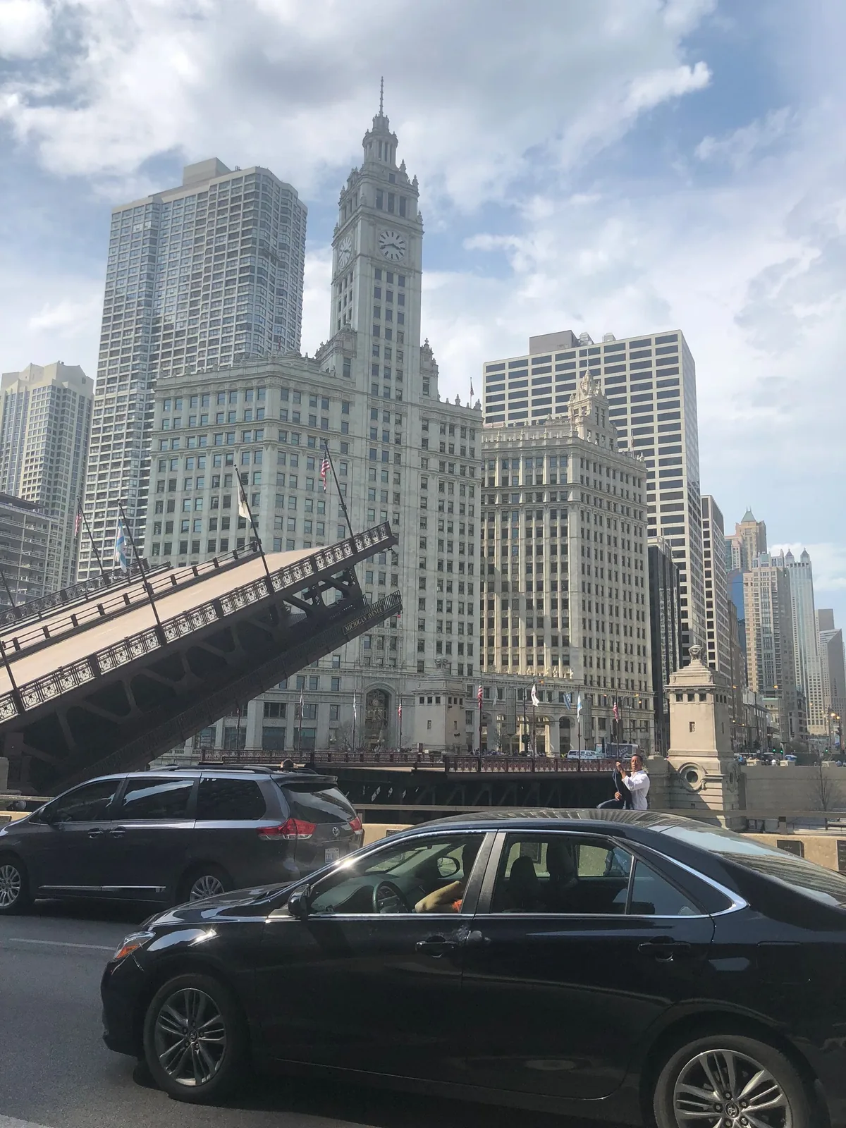 A raised drawbridge with a historic tower and a car waiting below